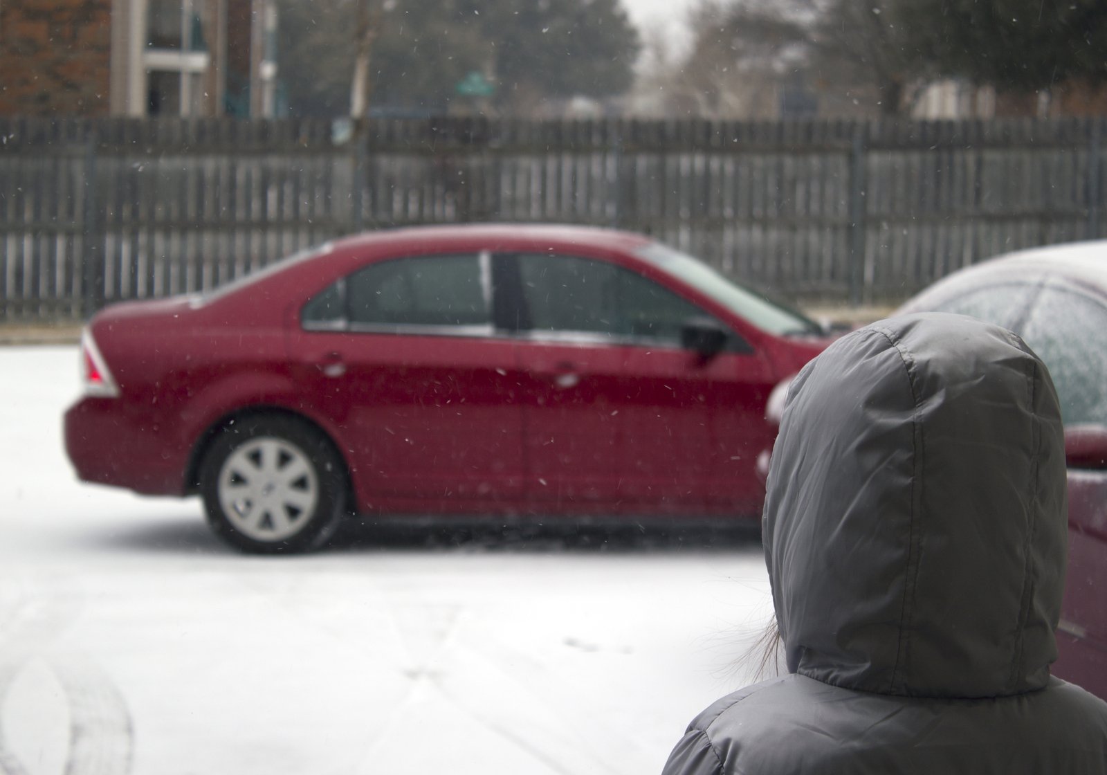 a person in winter clothing next to cars