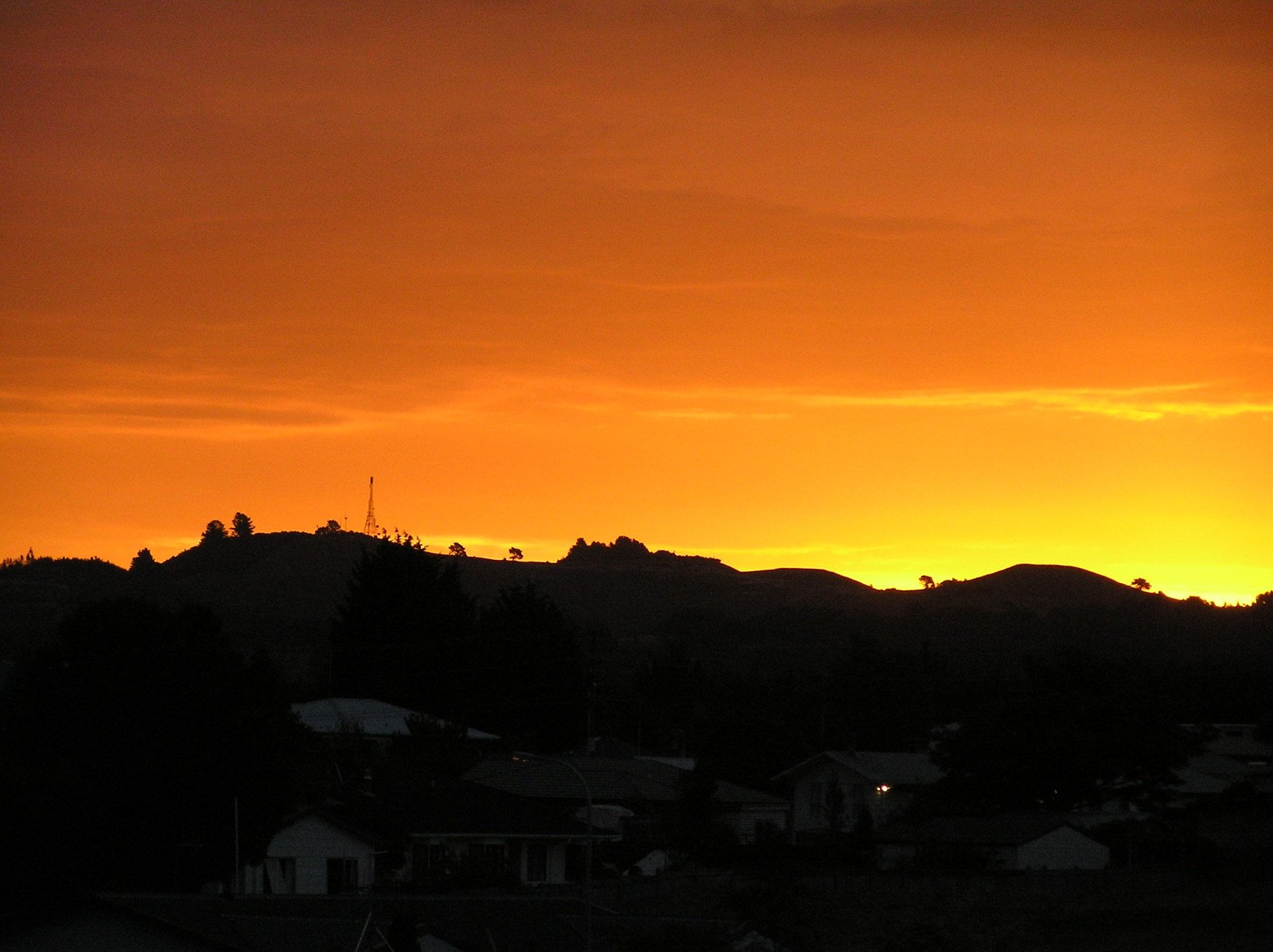 sunset behind a city landscape, with homes and hills