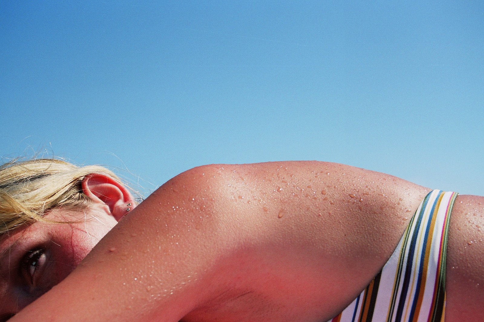 a woman laying on a white bench under a blue sky