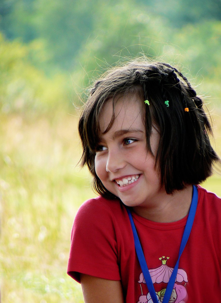 a child is smiling and wearing an award on her necklace
