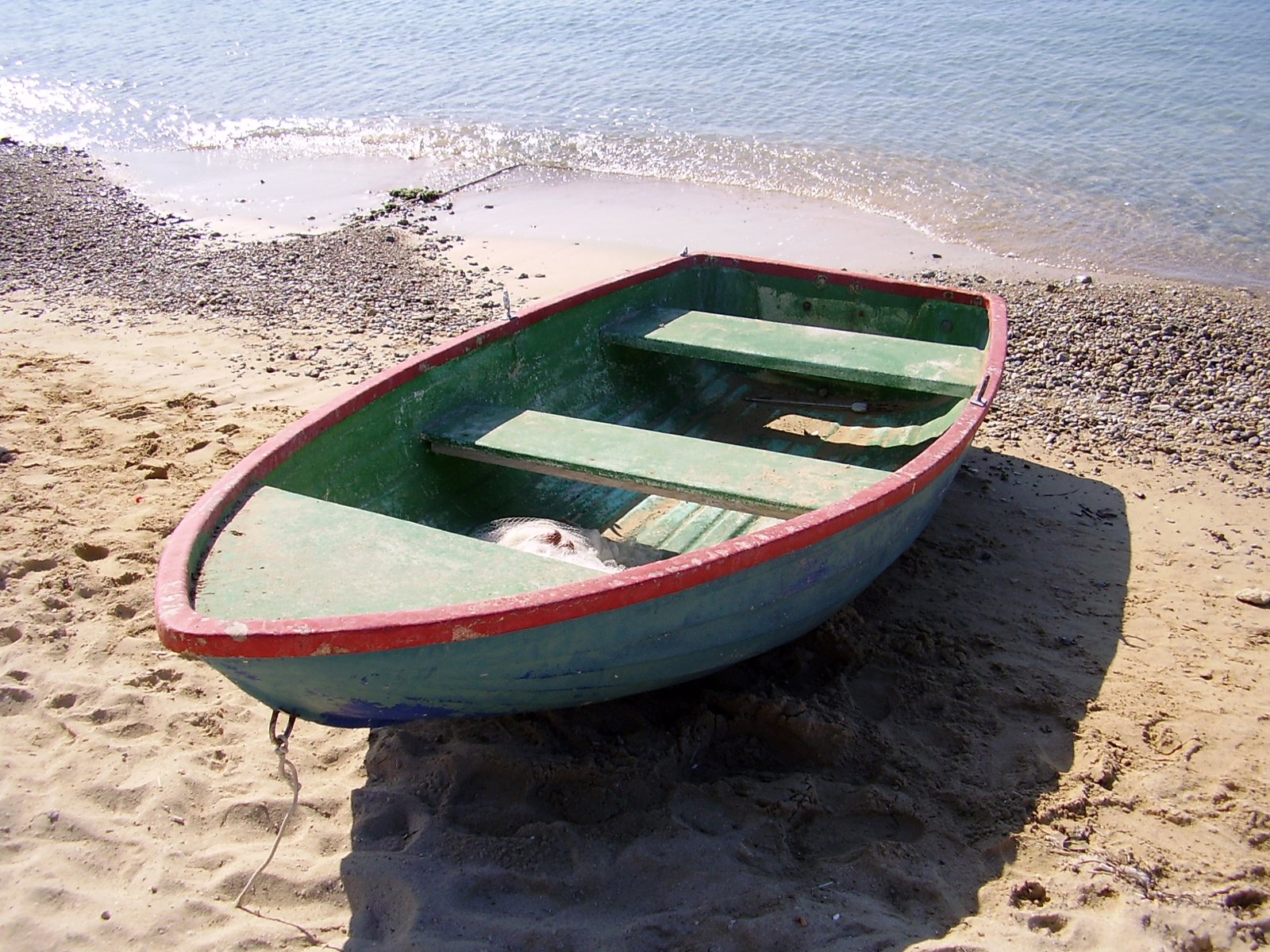 a boat sitting on top of the sand next to the ocean