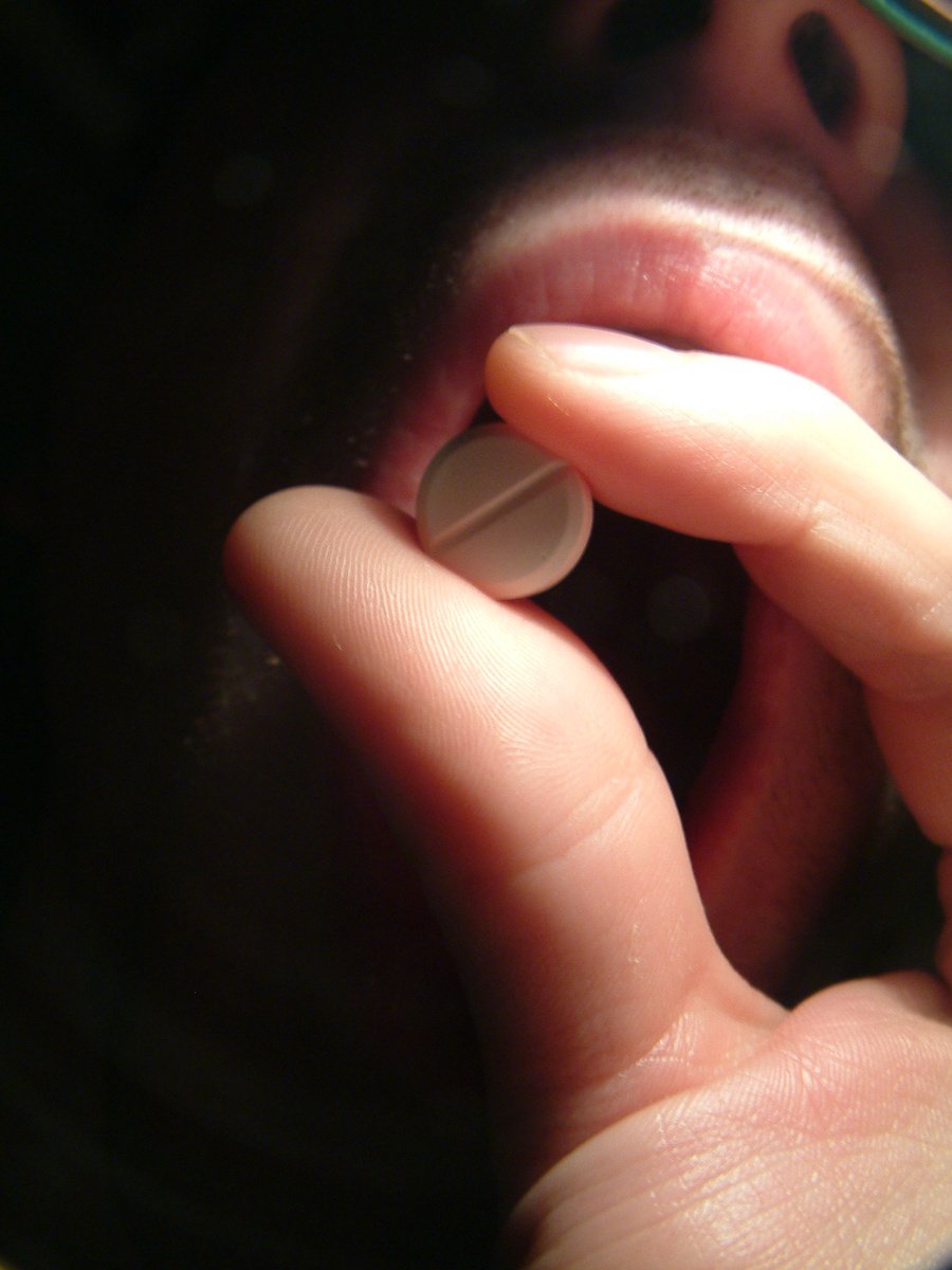 a man's mouth with a pill sticking out of it