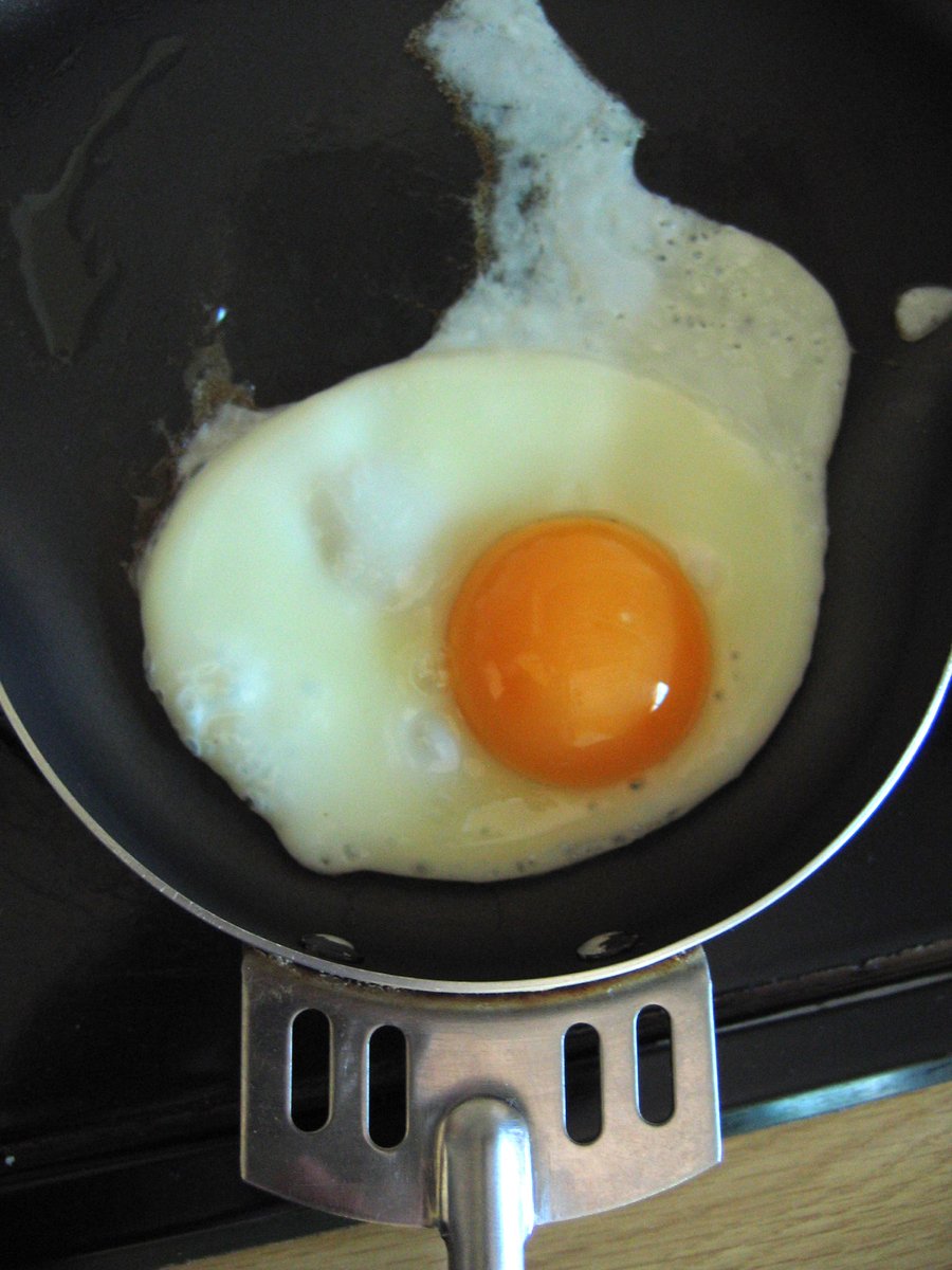 fried egg on plate cooking in pan over stove burner