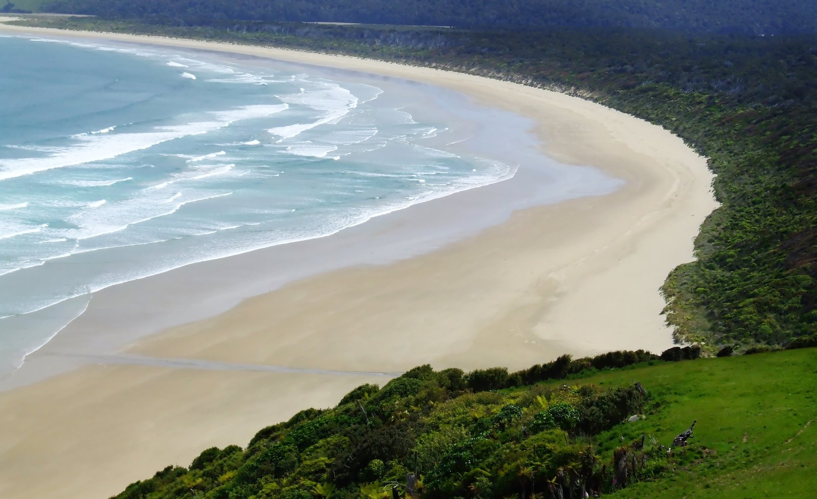 the shoreline of an empty beach with many waves coming into the shore