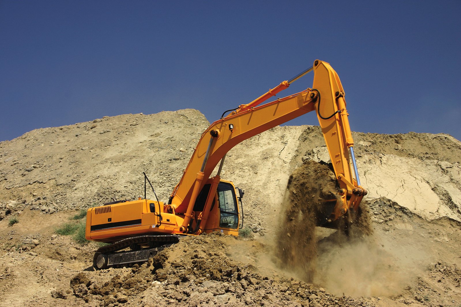 an excavator digging dirt in the middle of the desert