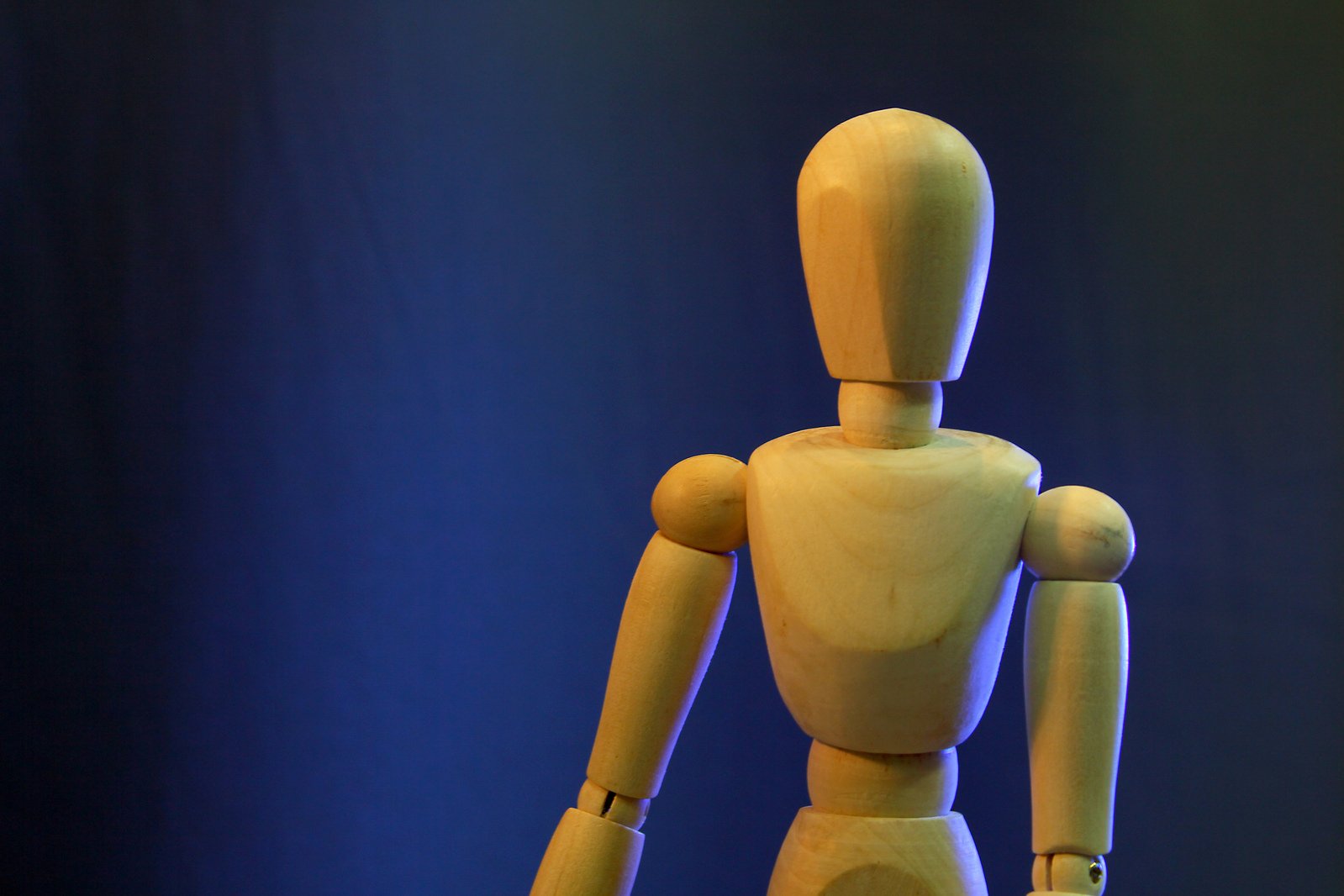 a yellow mannequin with wooden arms and legs