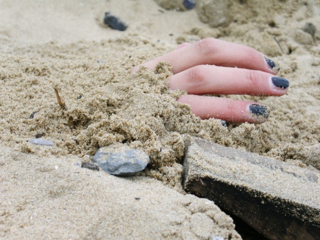 a hand reaching out for a piece of food in the sand