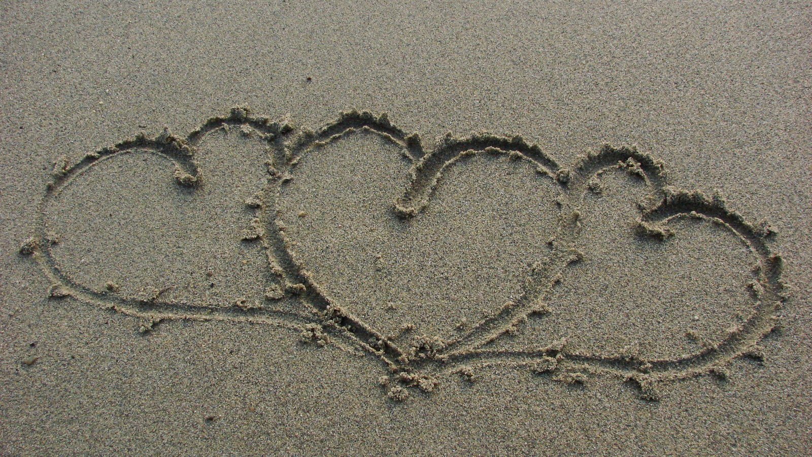 two hearts shaped in sand drawing into the sand