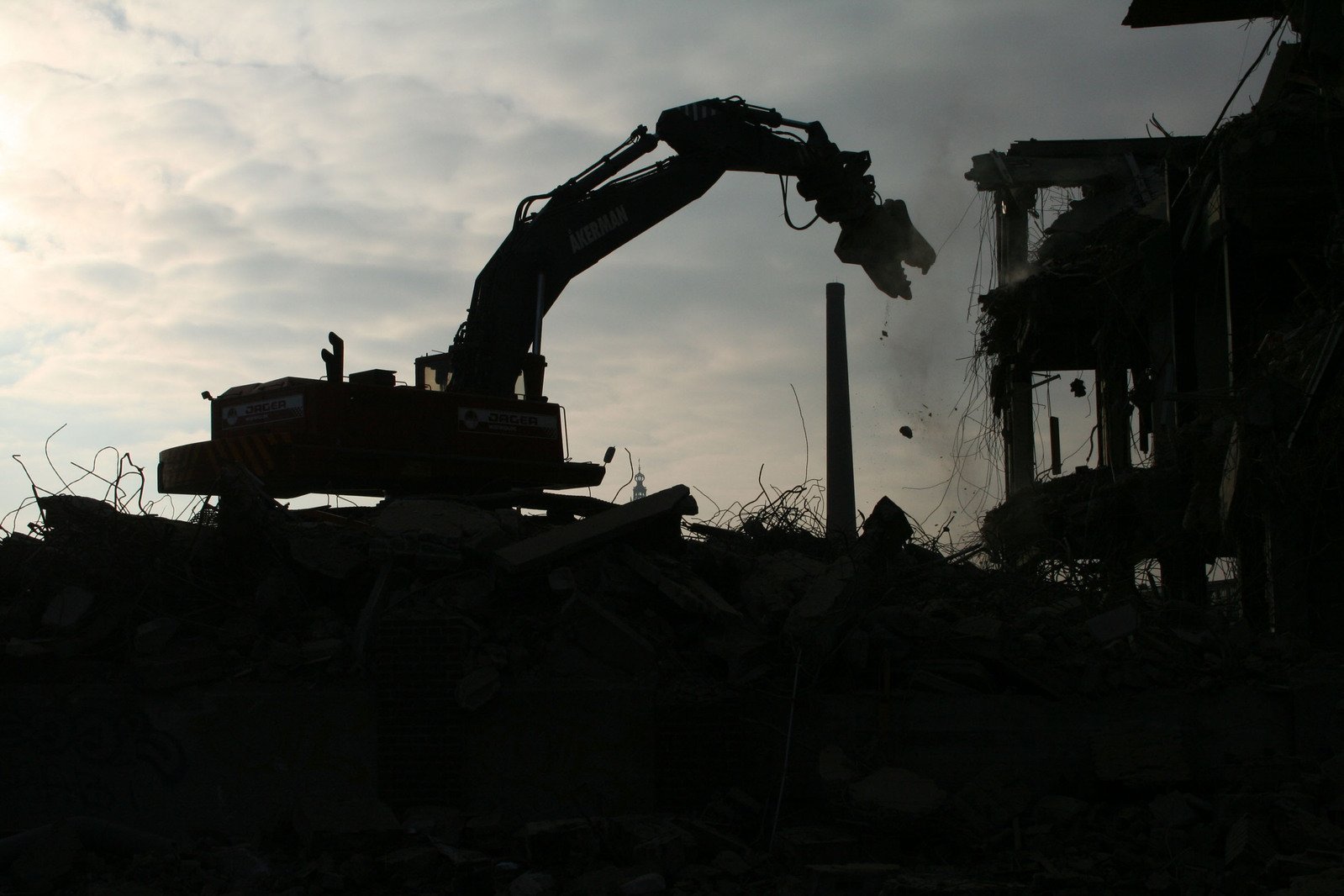 the silhouette of the excavator is behind the construction site