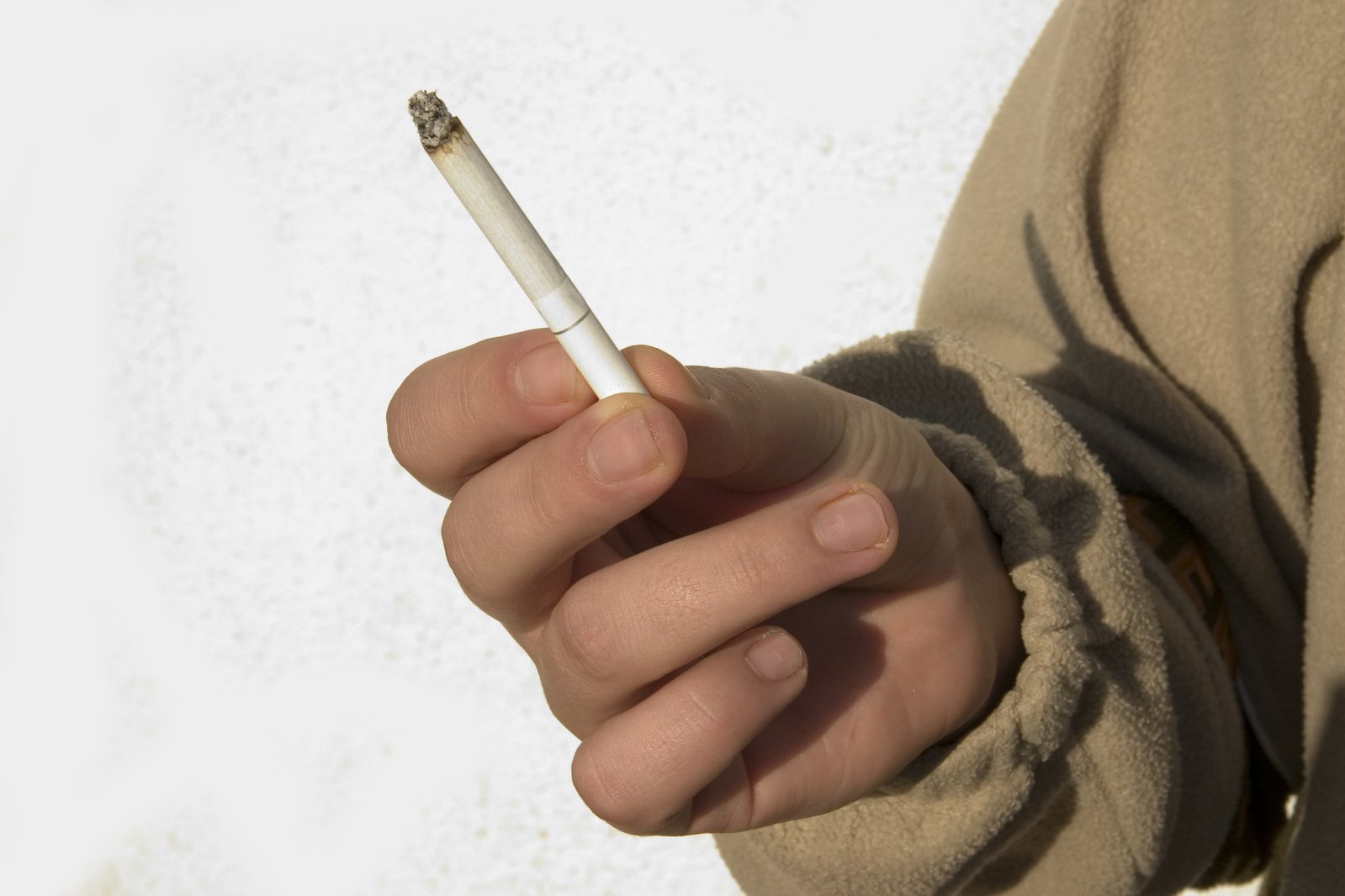 the fingers of a person holding a cigarette in their right hand