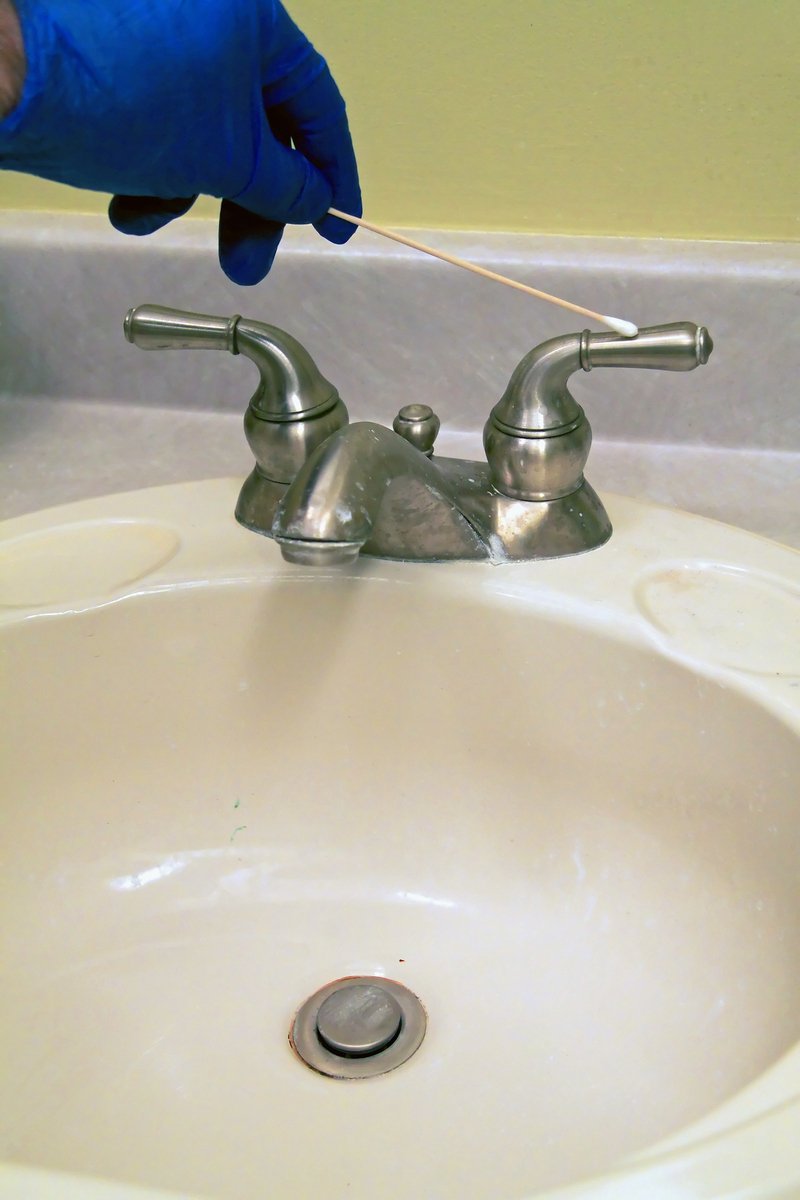 a person in blue gloves holding a needle near a sink