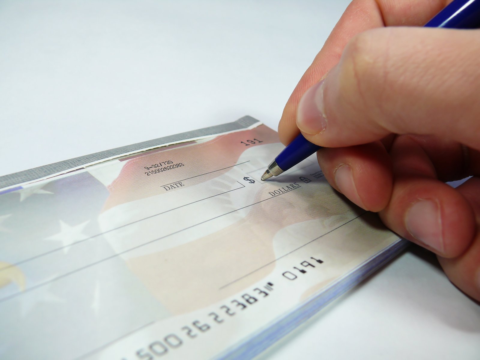 hand holding pen and writing in a paper check