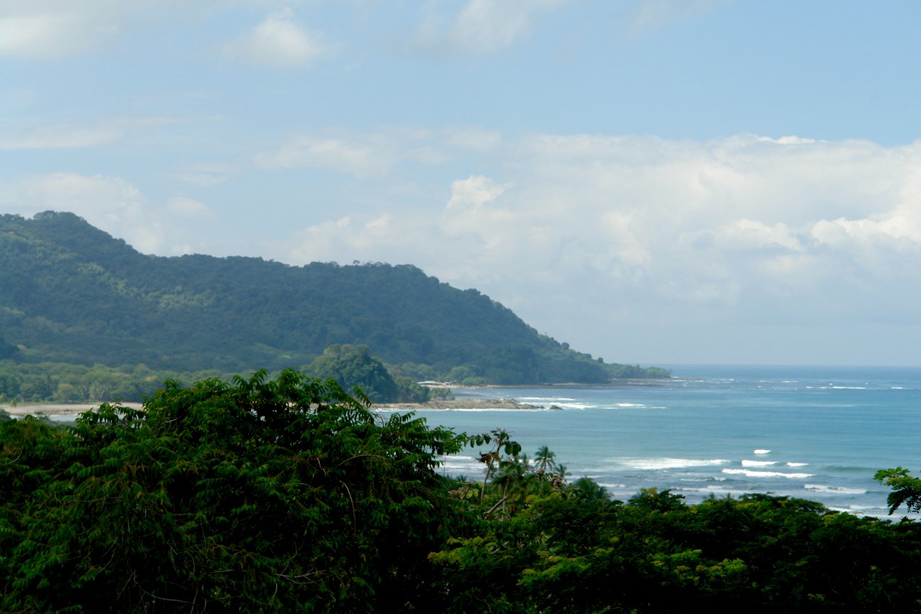 green mountain overlooking a beach and ocean on a clear day