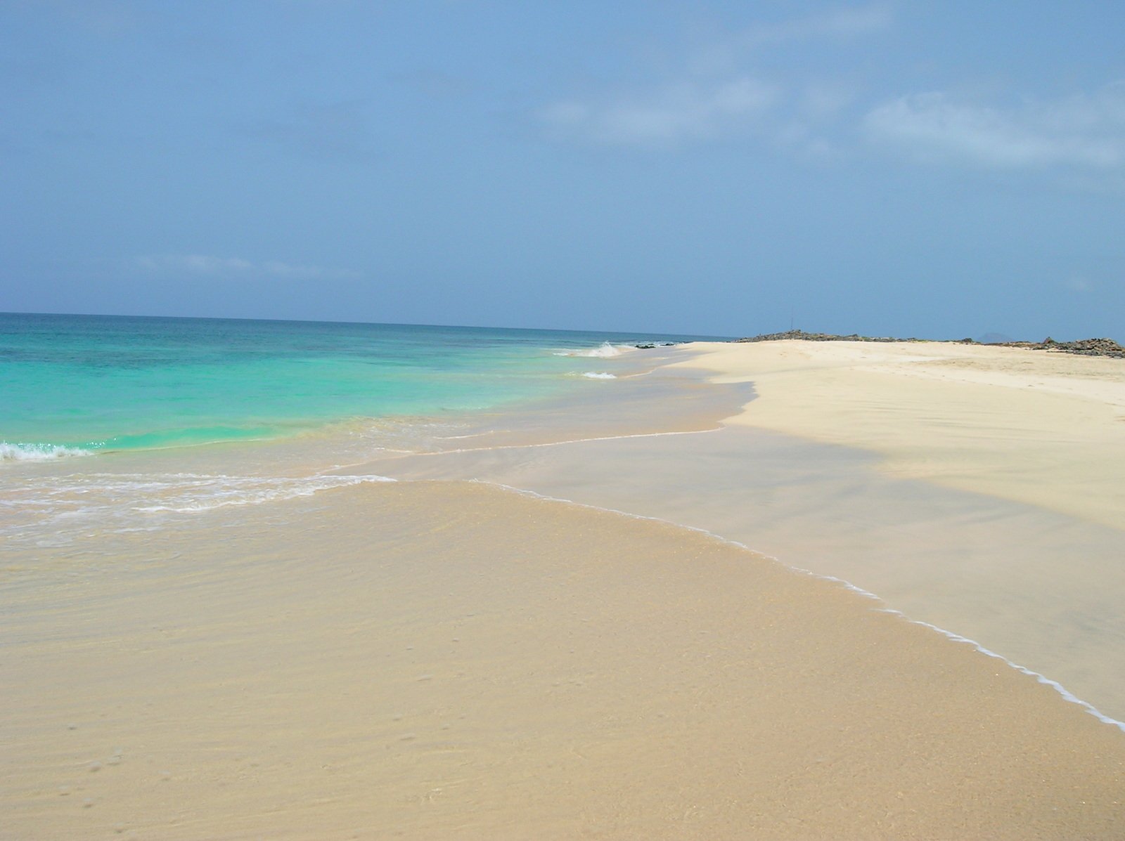 blue water waves on a sandy beach and blue sky