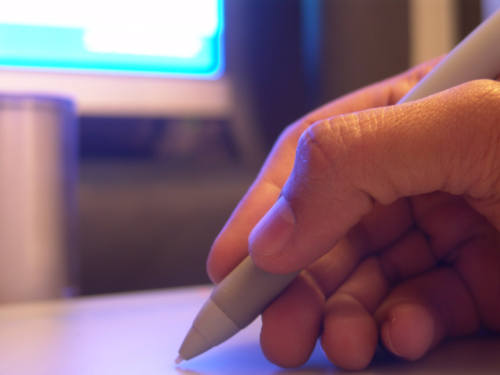 hand holding a white plastic pen next to computer keyboard