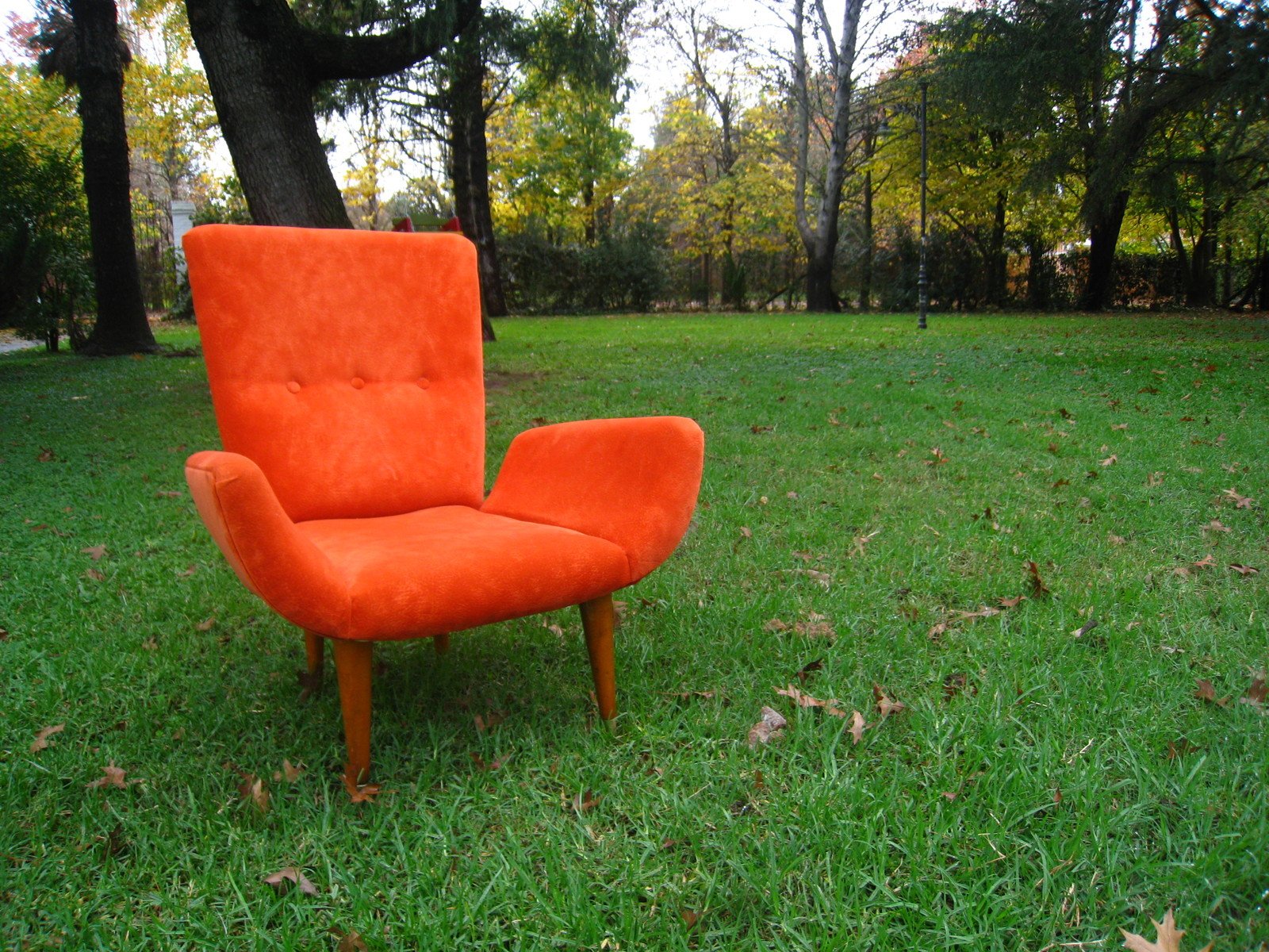 an orange chair sitting in the middle of a field