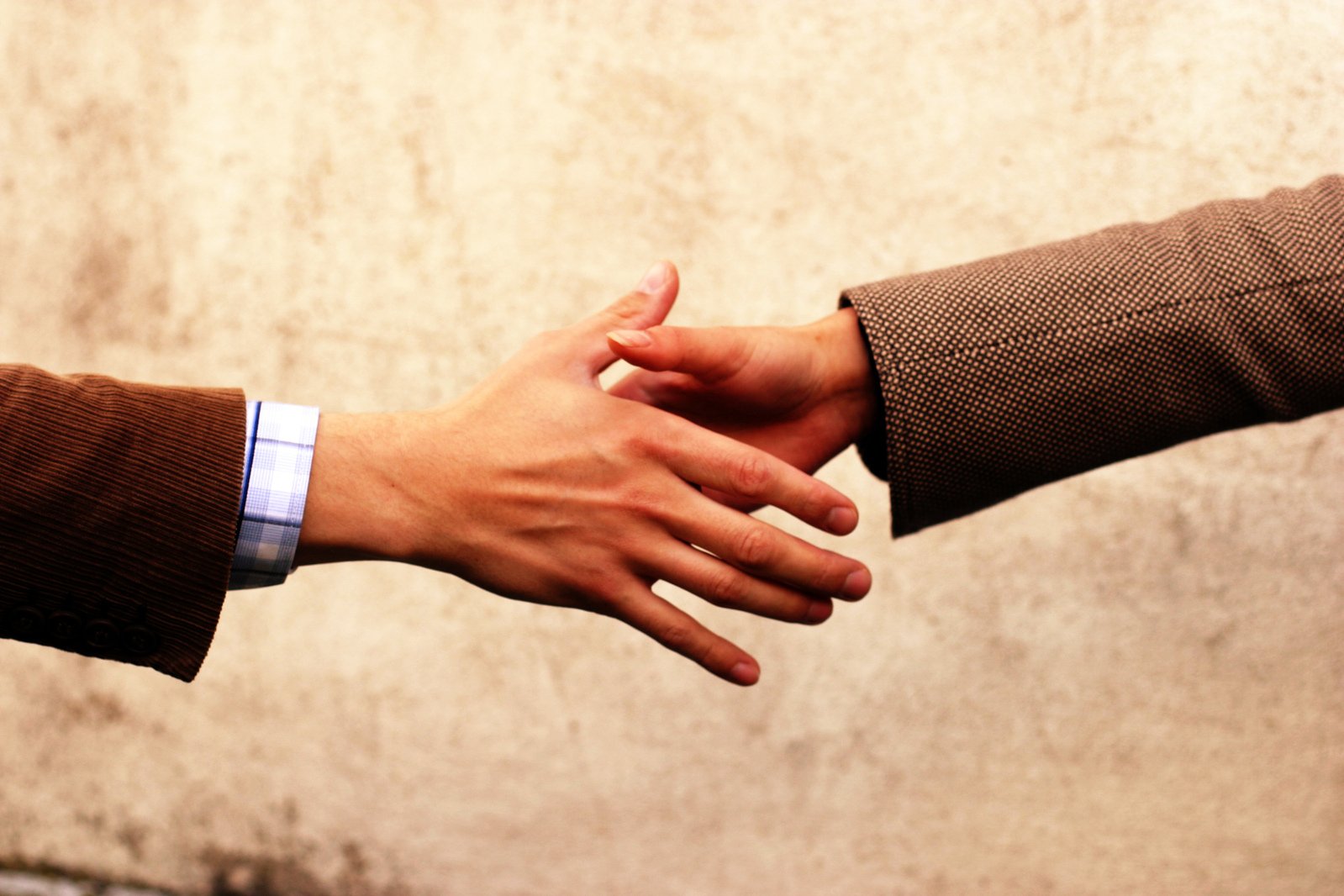 two people holding hands over each other while wearing suits