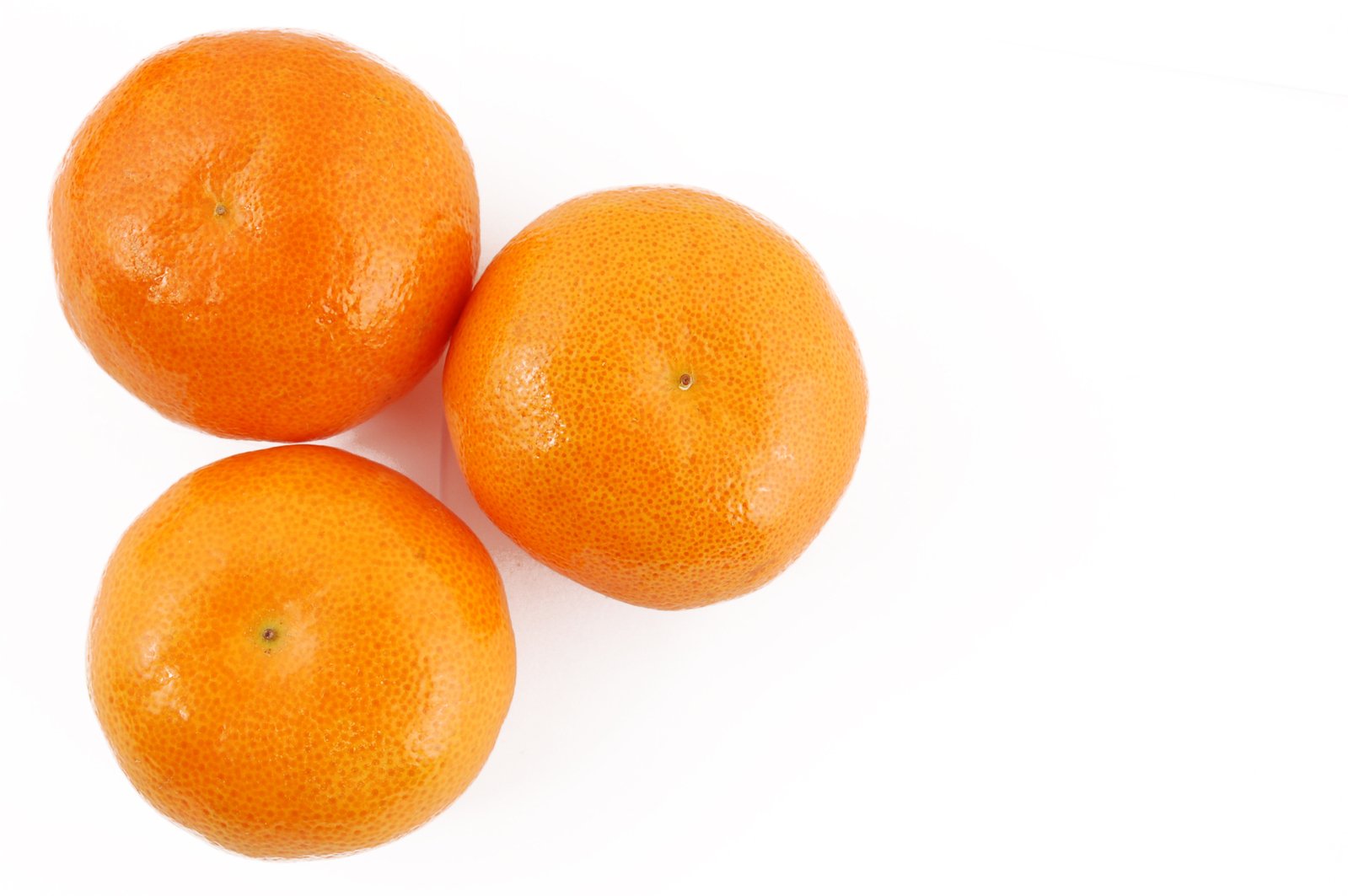 three oranges sit side by side on a white surface