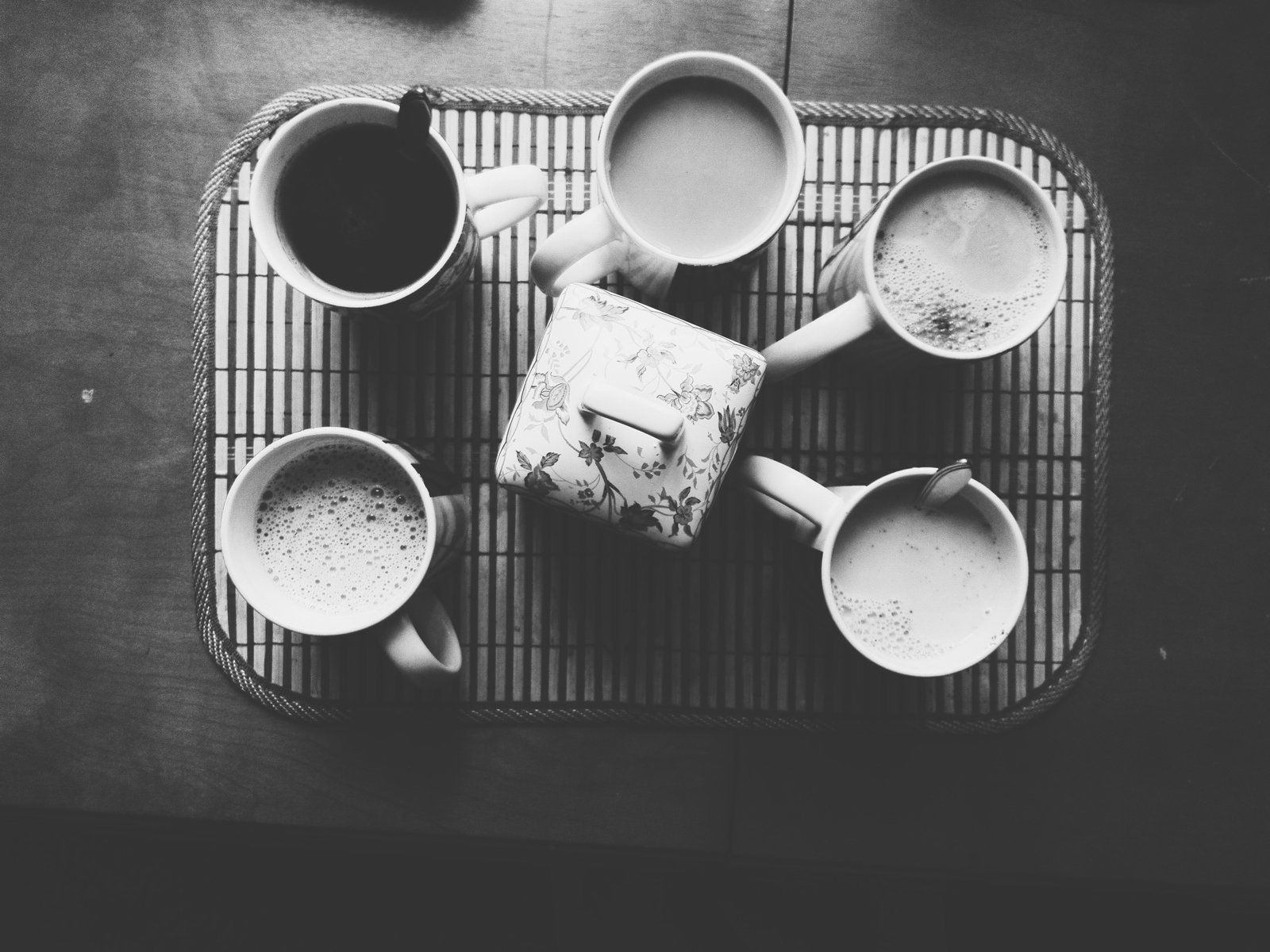 four mugs of coffee sitting on top of a bamboo mat