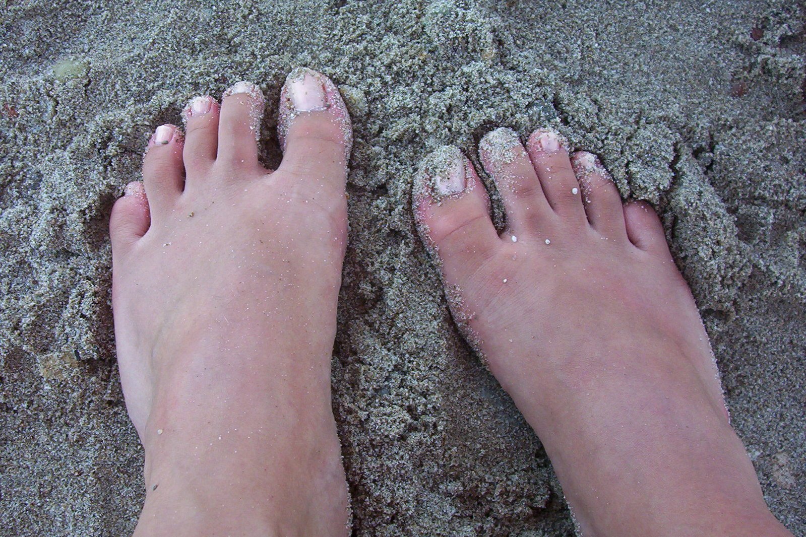 feet and ankles are covered with sand as it is almost completely white