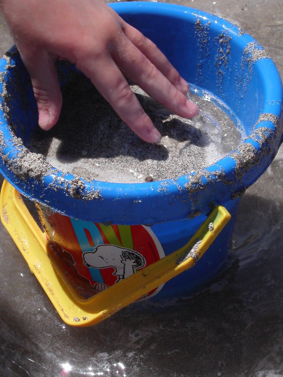 a child is mixing sand in a blue bath