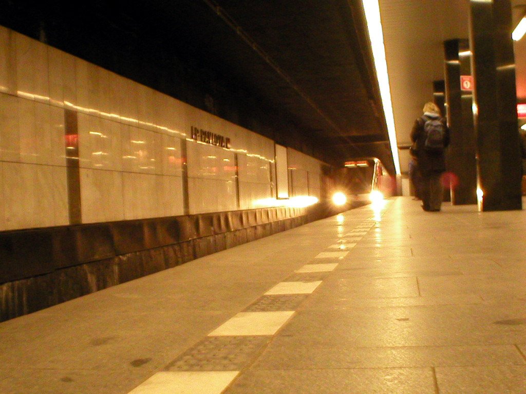 a subway platform with two people on the other side