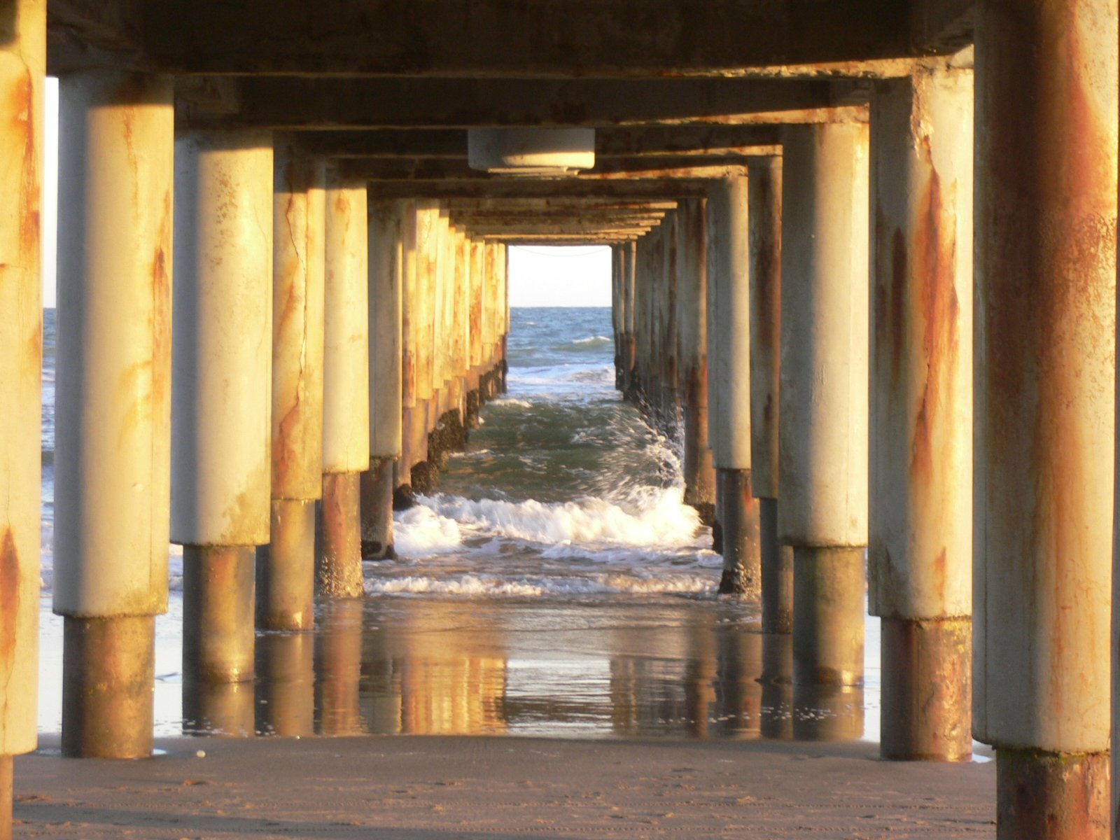 a view of the ocean with several old pillars in the foreground