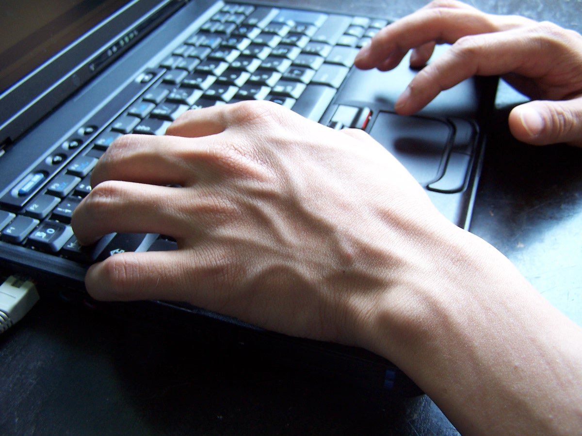 a person with their hand on a computer keyboard