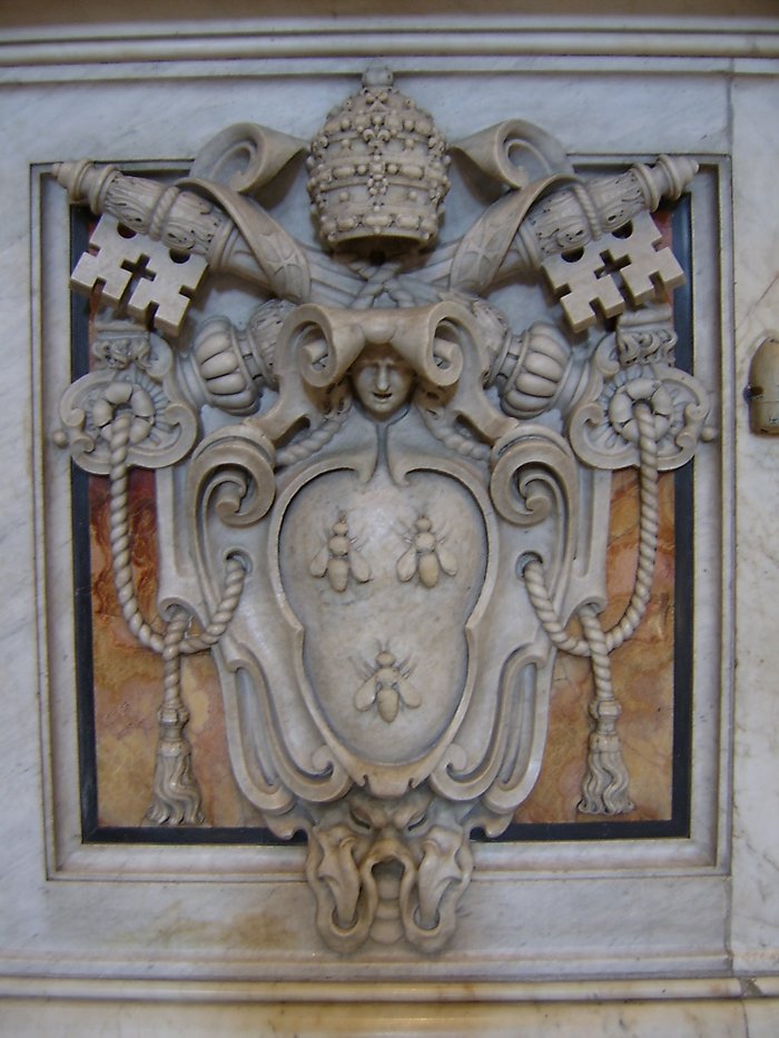 a statue with a coat of arms on the side of a building