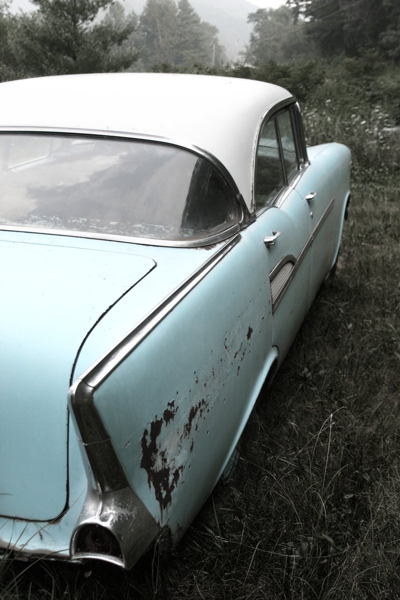 an old, dusty blue car that is parked on the grass