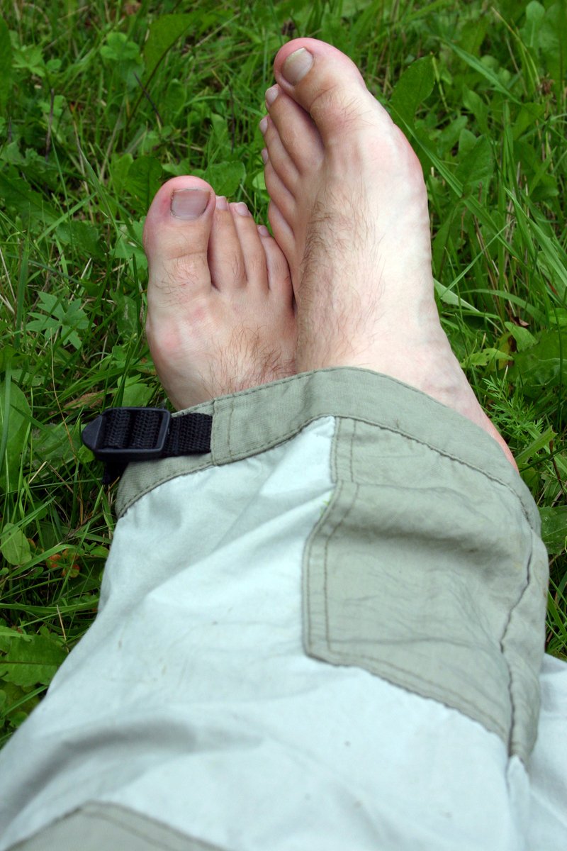 someone with bare toe laying on green grass