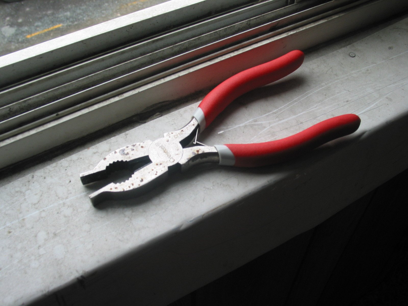 a red pair of scissors is lying on a window sill