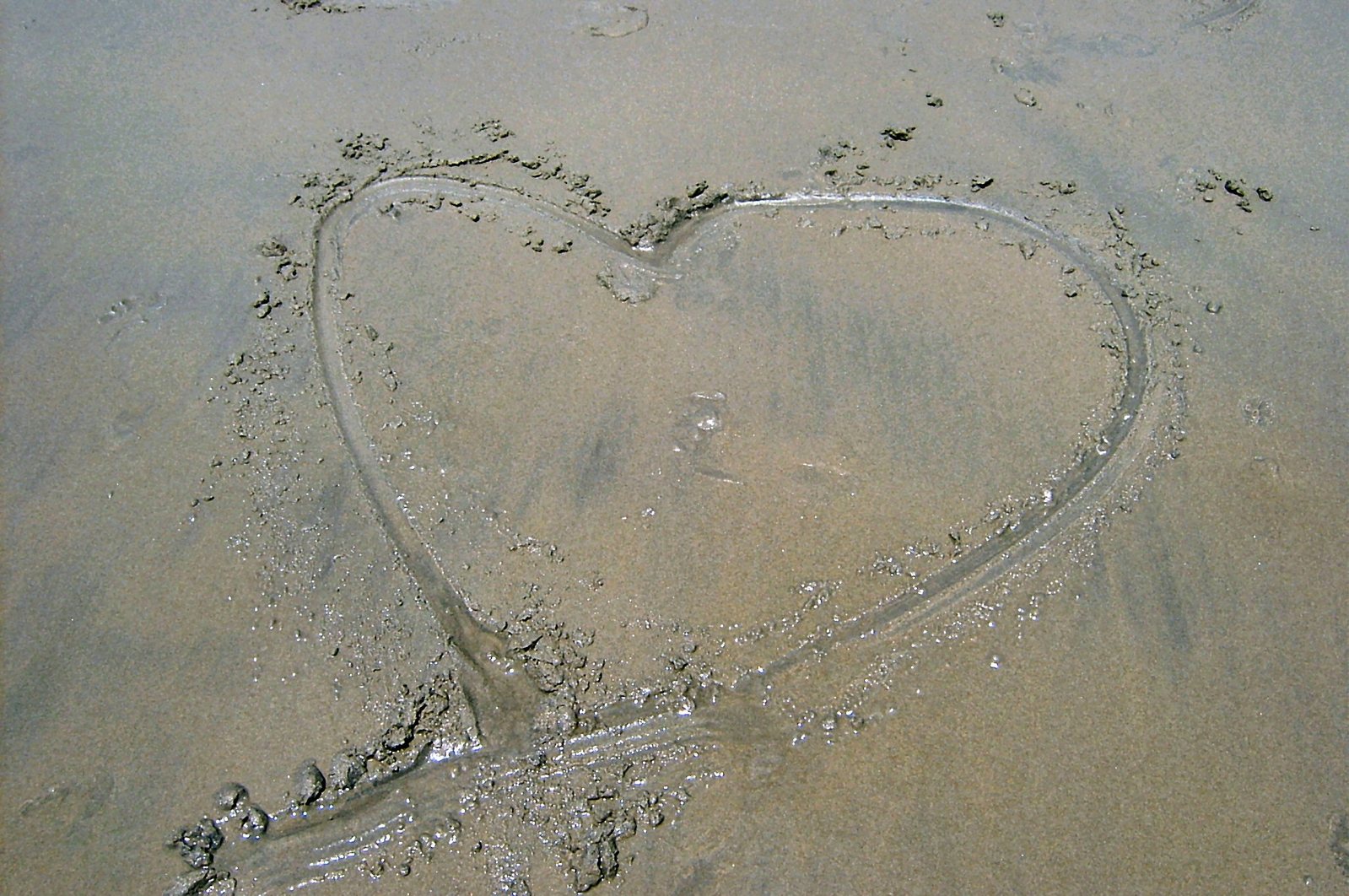 a heart - shaped heart is drawn in the sand at the beach