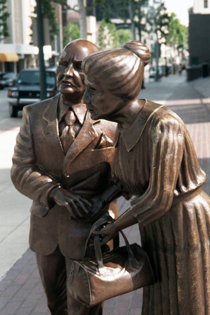 a statue on the sidewalk next to a woman