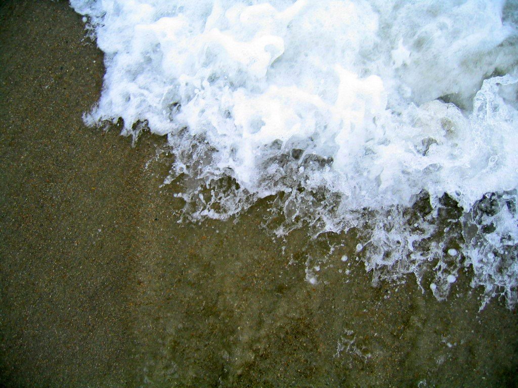 there is a very small wave crashing on the sand