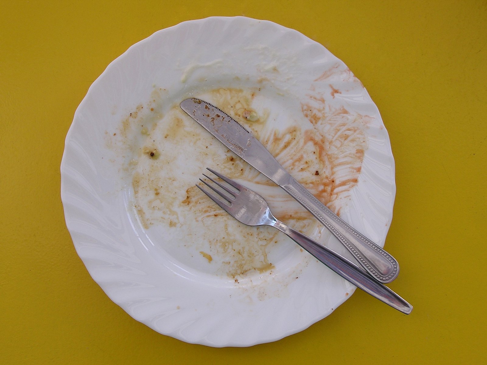 dirty white plate with half eaten fork sitting on yellow table