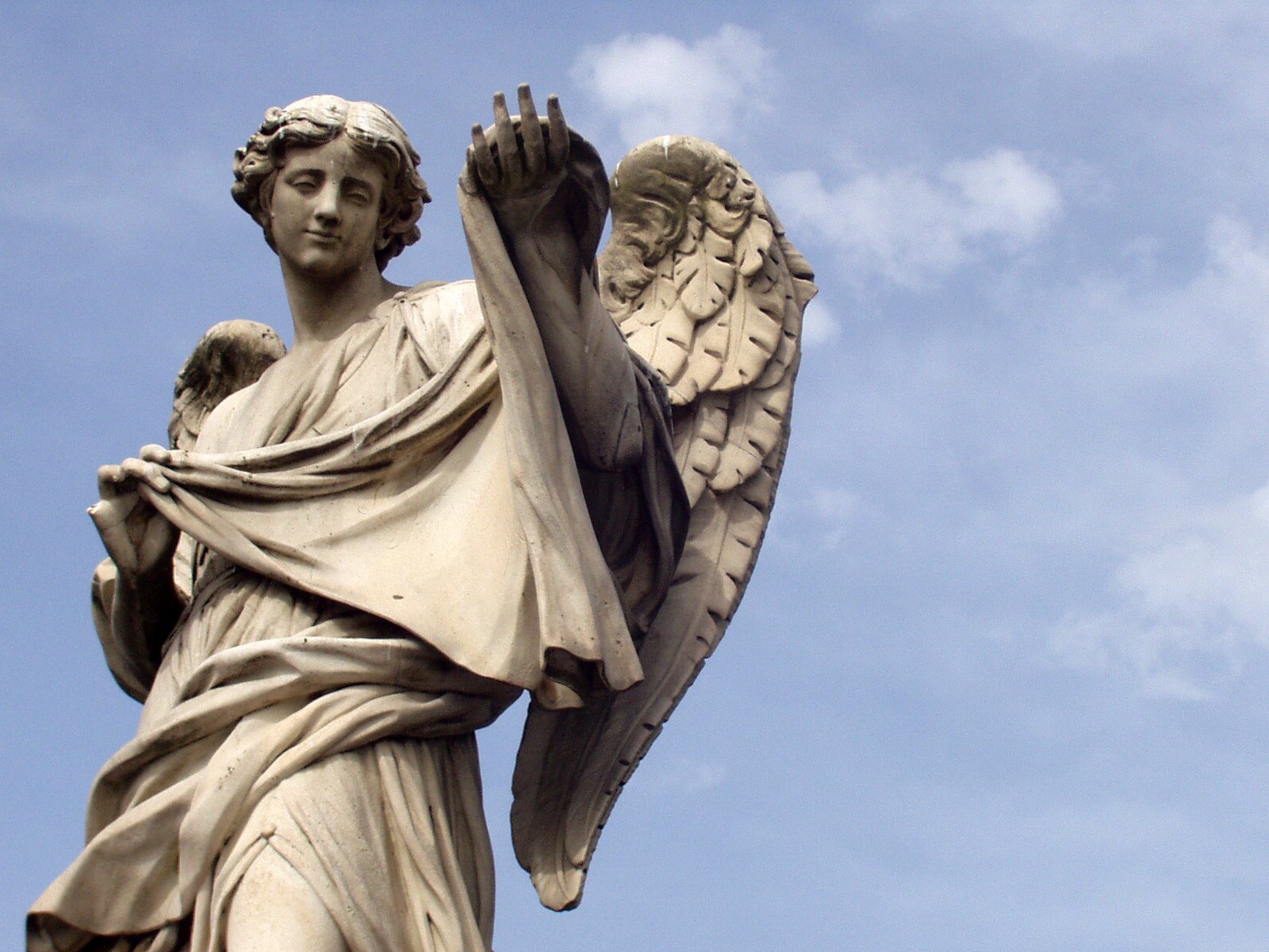 statue of an angel with wings against a blue sky