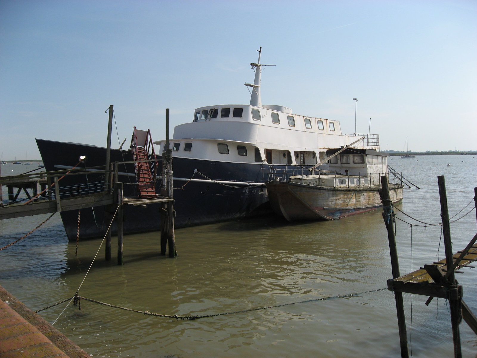 large docked boat at dock with multiple ropes and poles