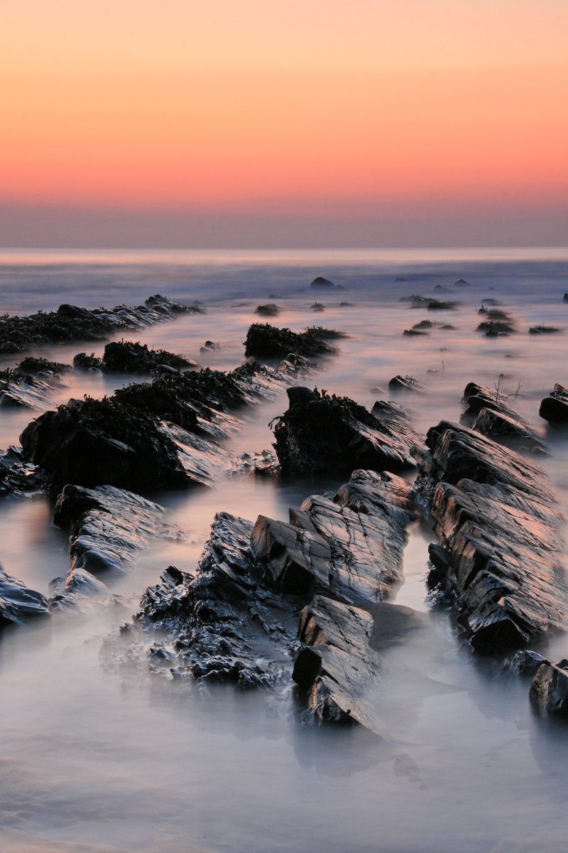 several rocks and the ocean during a sunset