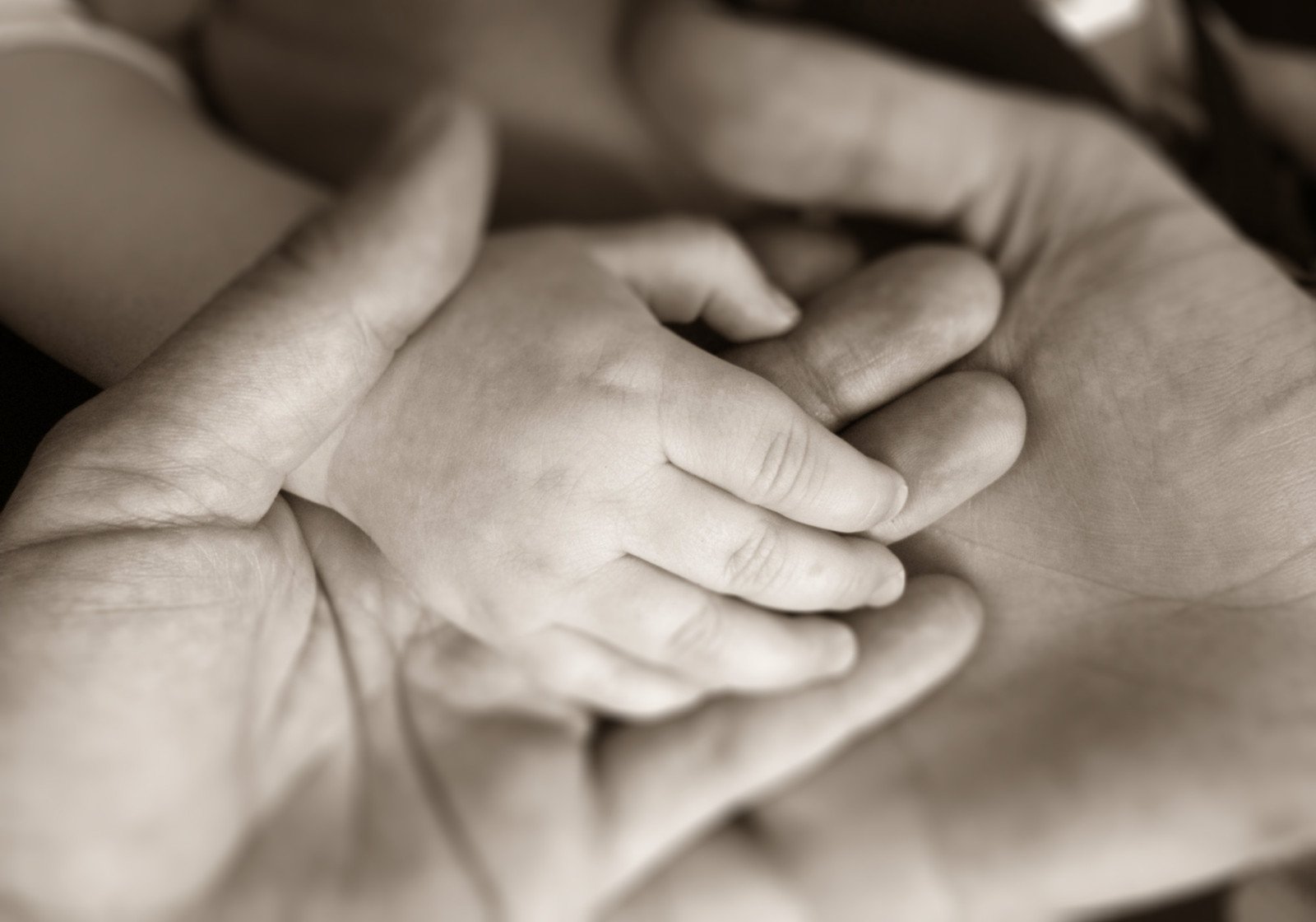 a couple is holding hands over the top of a baby