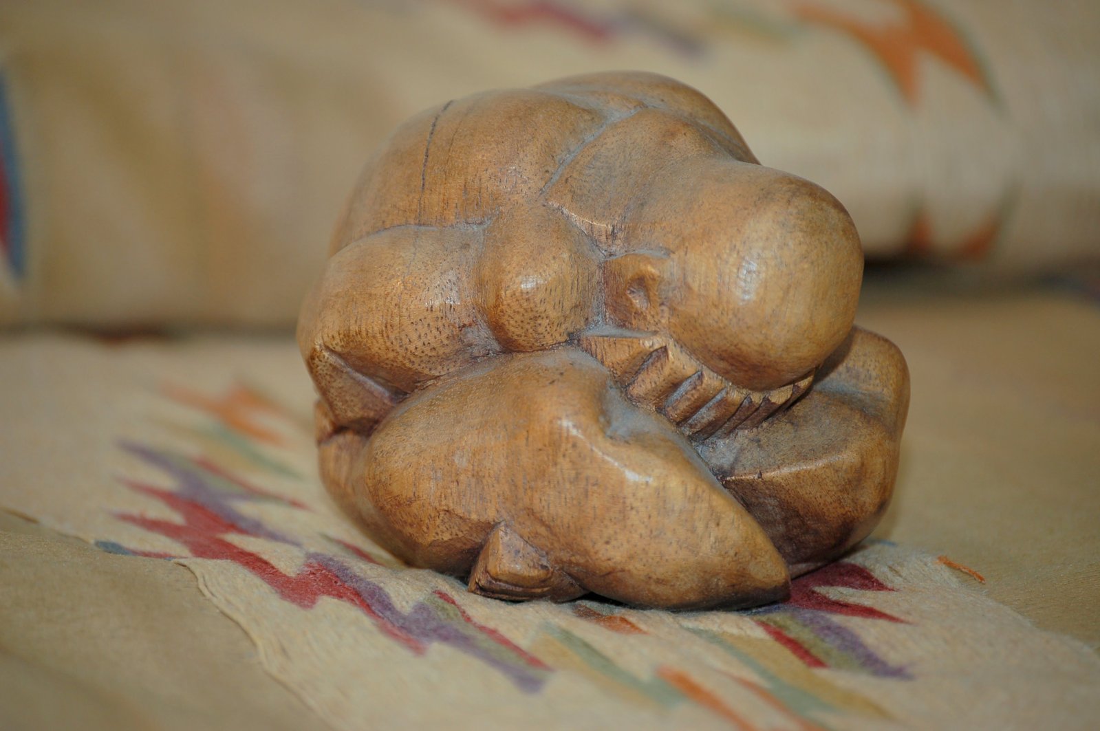 an intricately carved wooden statue lies on a cushion
