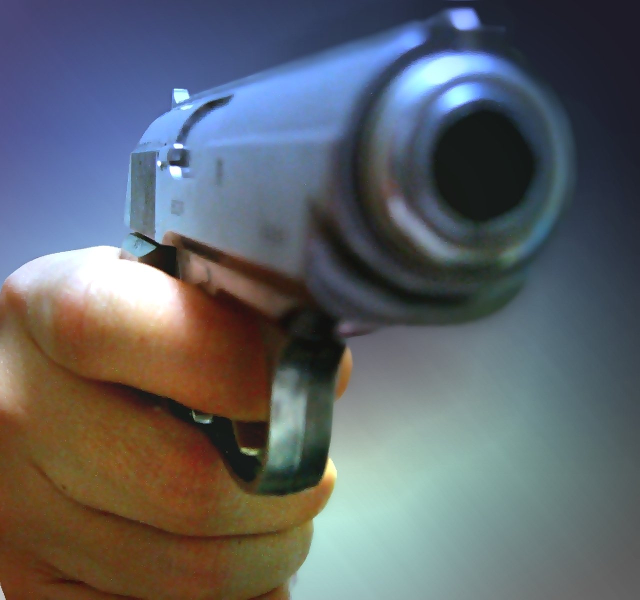 a person pointing a small silver gun towards the camera