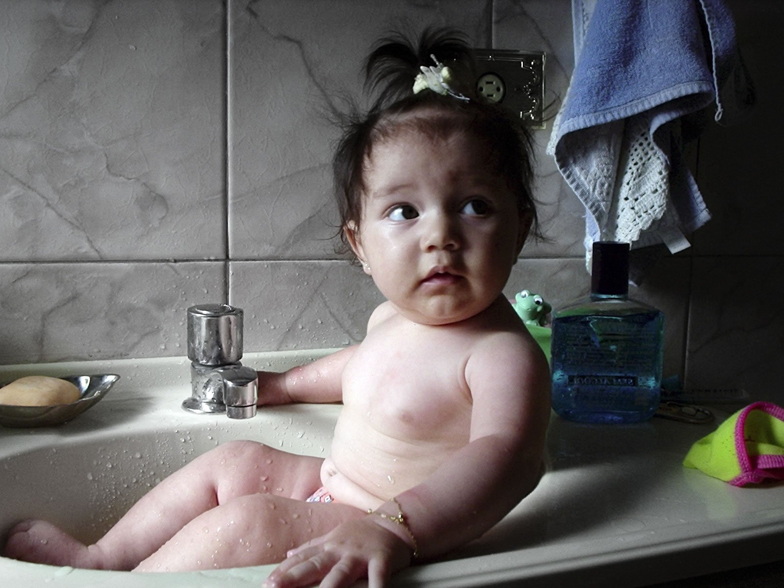 a child sits in a bathroom sink as it appears to be having a bath