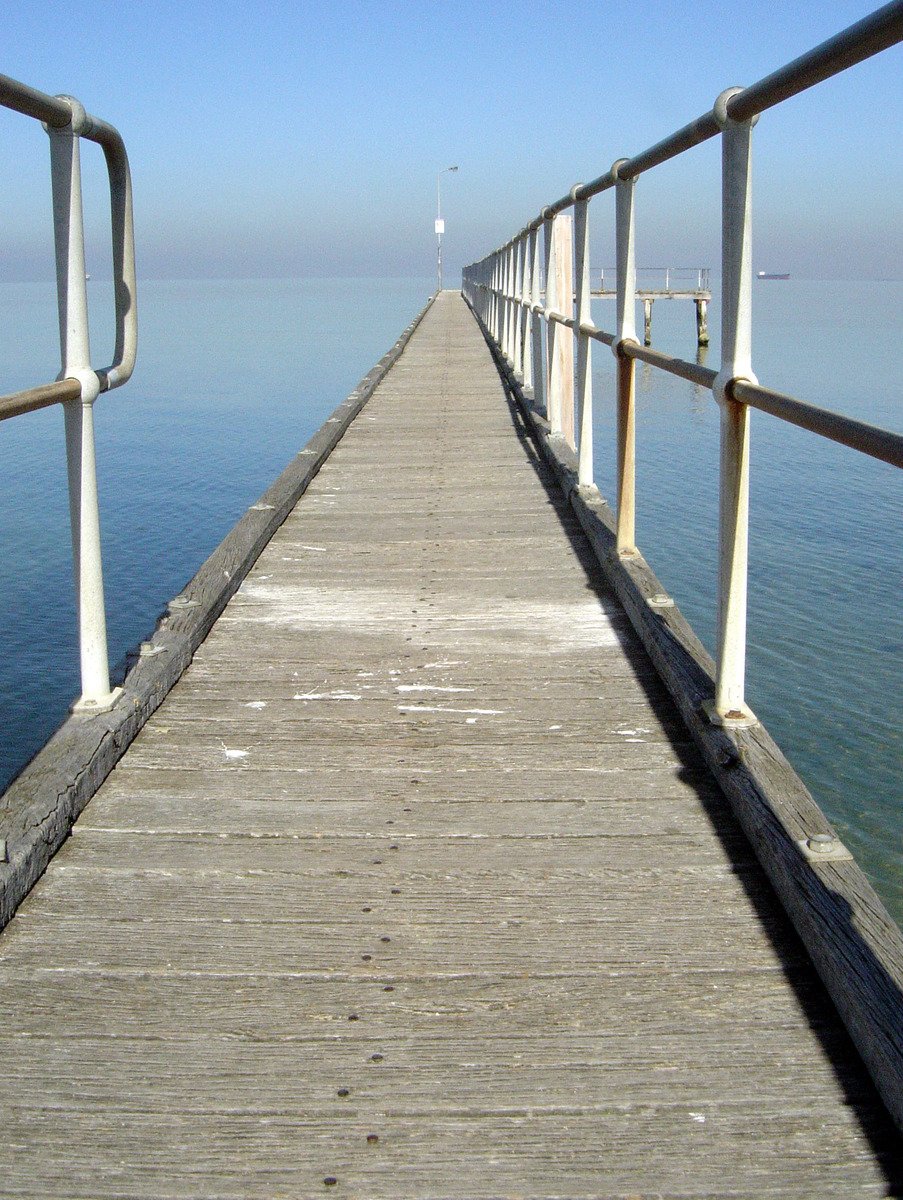 the pier at the end of the beach has many posts