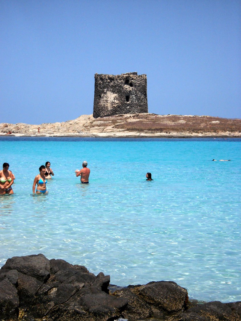 people standing in the ocean near a rocky beach