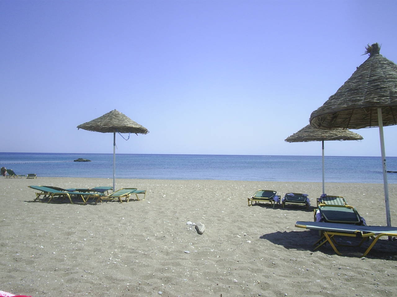 the chairs are lined up under straw umbrellas on the beach