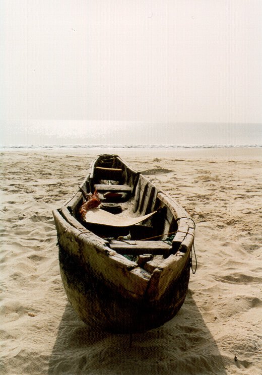 a small wooden boat rests on the sand