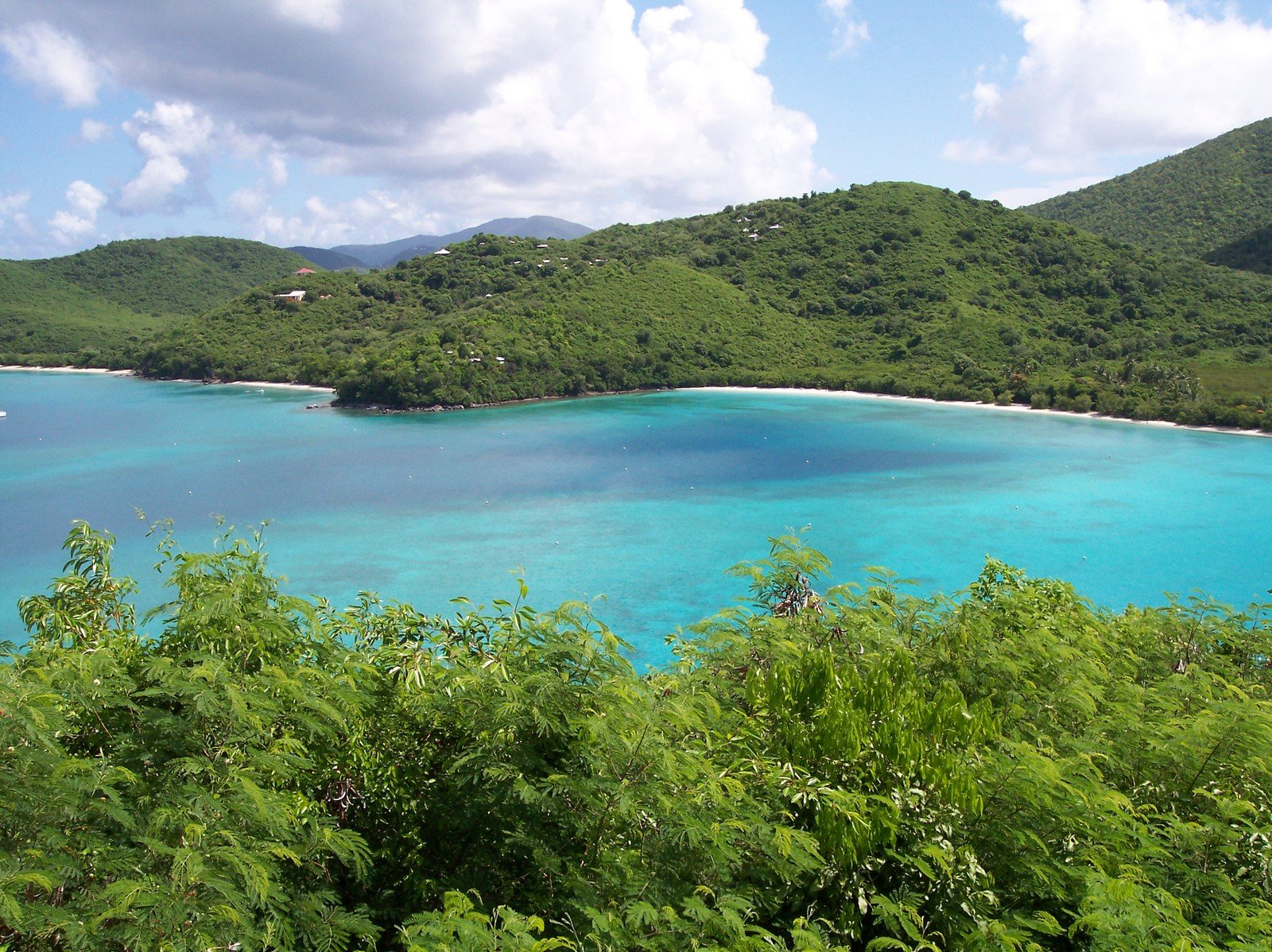 the blue water and white beach are surrounded by tropical vegetation