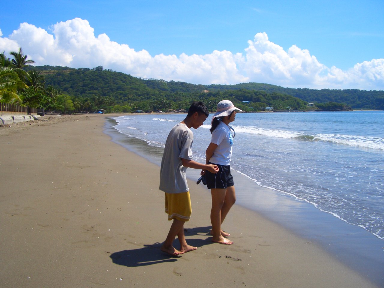 two people stand on the beach facing each other