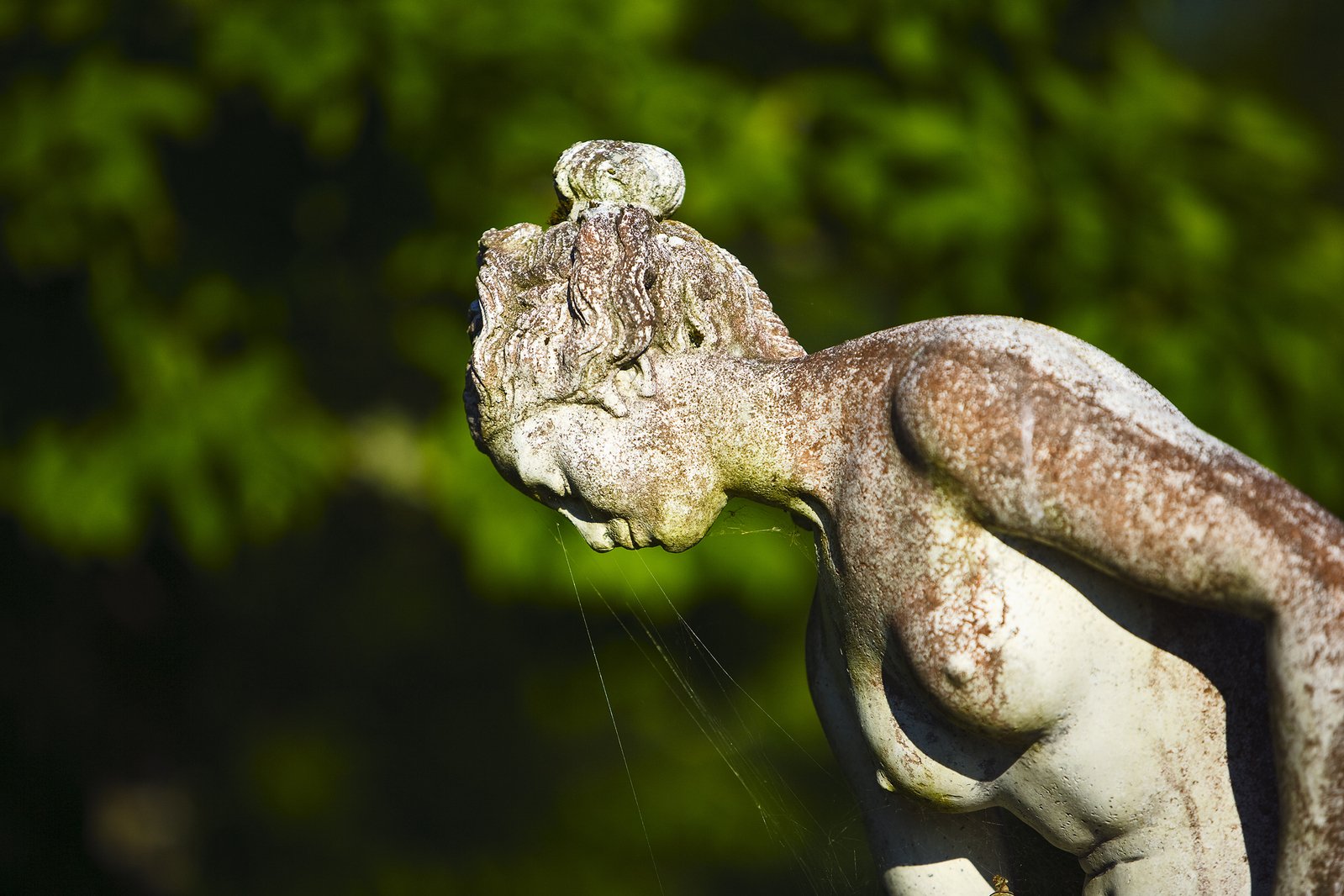 an old statue with moss growing from it